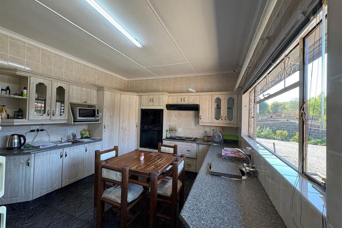 A functional kitchen featuring built-in cabinetry, integrated oven and hob, granite countertops, and a large window providing natural light.
