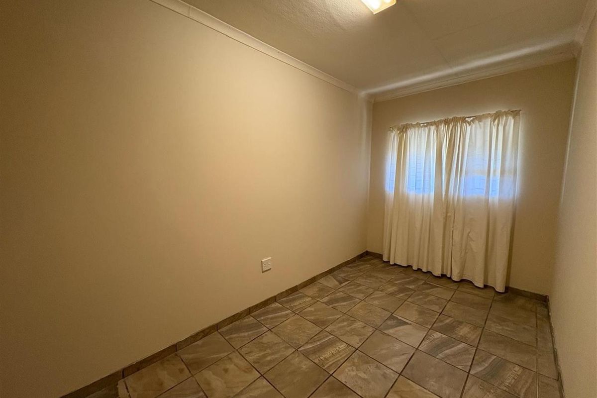 A simple, empty bedroom featuring tiled flooring and neutral wall finishes, providing a blank canvas for personalization.