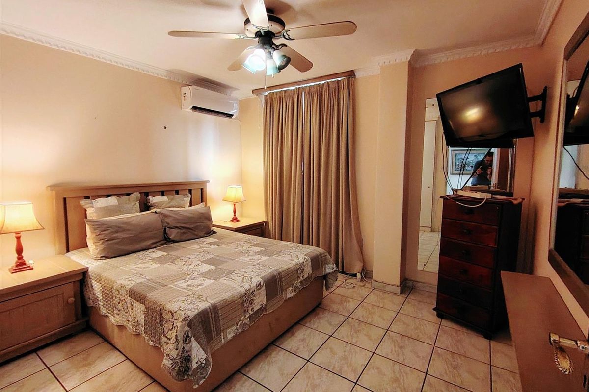 A bedroom featuring tiled flooring, a ceiling fan, and a wall-mounted air conditioning unit.