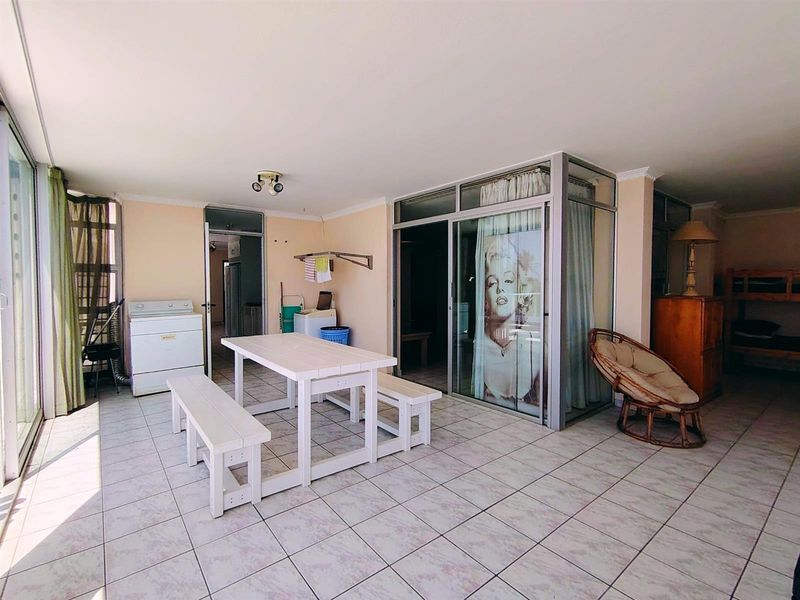 A spacious enclosed patio or sunroom featuring tiled flooring, large sliding glass doors, and direct access to adjacent interior living spaces.