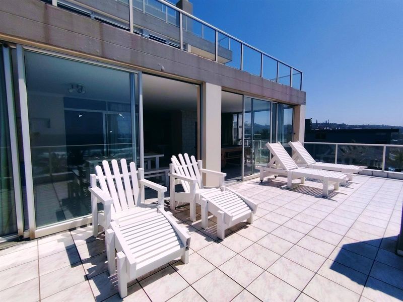 Spacious apartment balcony featuring tiled flooring, glass balustrades, and large sliding door access to the interior living area.