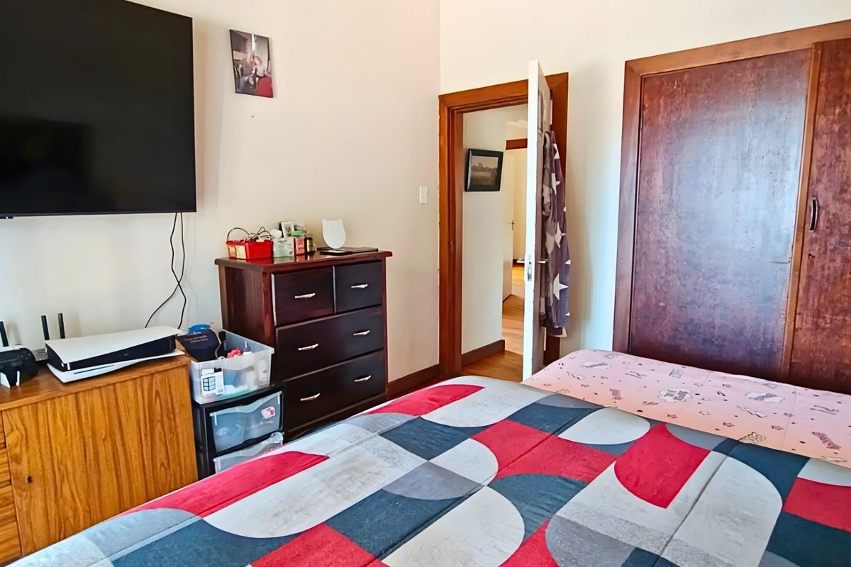A bedroom featuring a built-in wooden wardrobe, wooden door frame, and neutral wall finishes.
