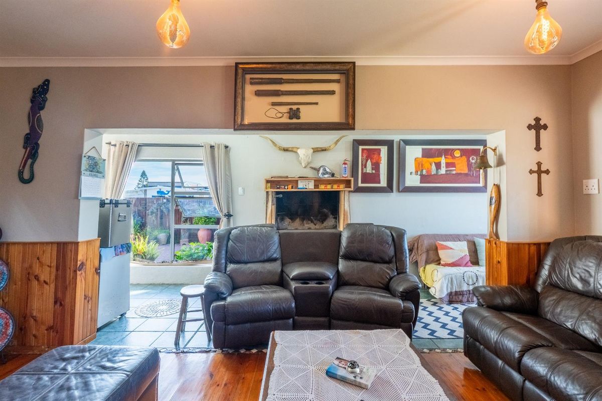 A living room featuring timber wall paneling, a built-in fireplace, and direct access to an outdoor patio area.