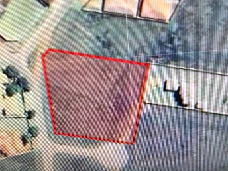 An aerial view of a vacant residential plot with a red boundary overlay indicating the property lines.