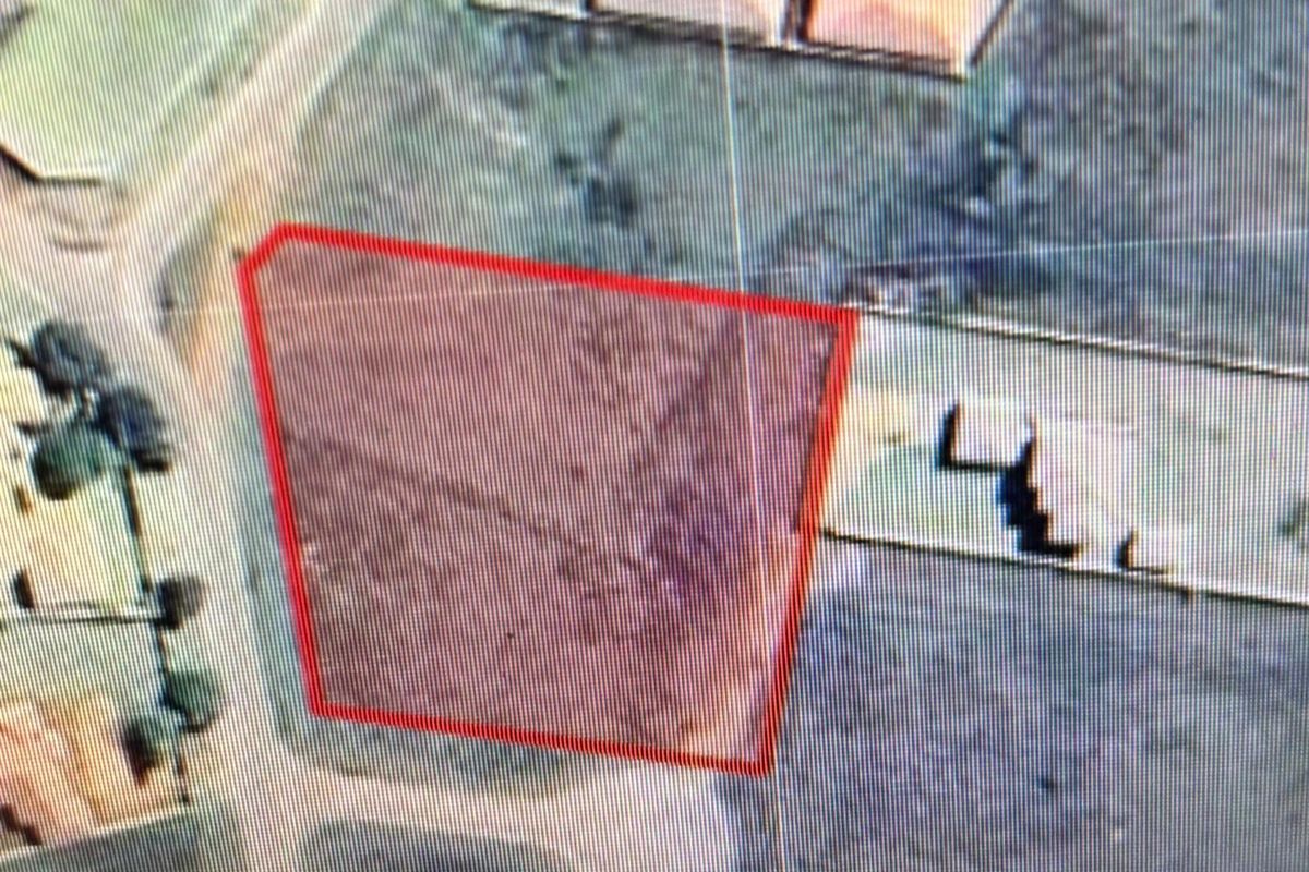 An aerial view of a vacant residential plot with a red boundary overlay indicating the property lines.