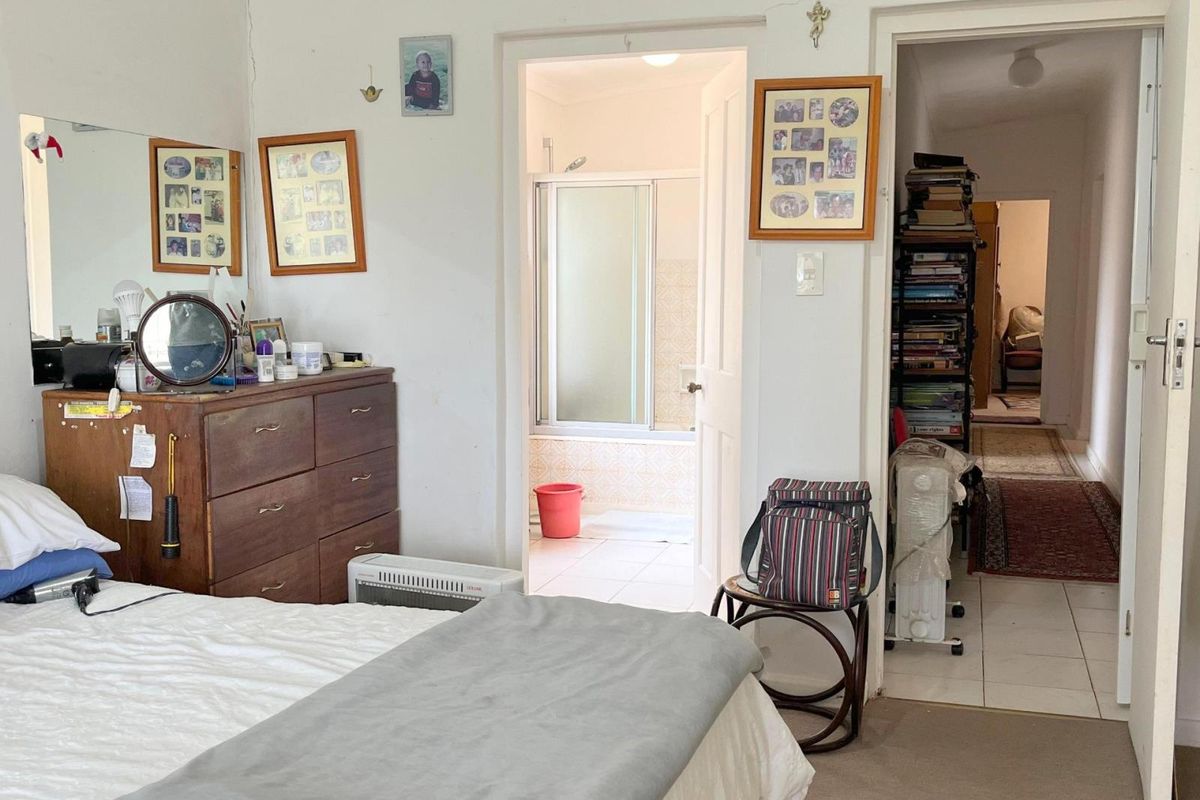 A bedroom featuring carpeted flooring, with an adjoining en-suite bathroom and access to a hallway.