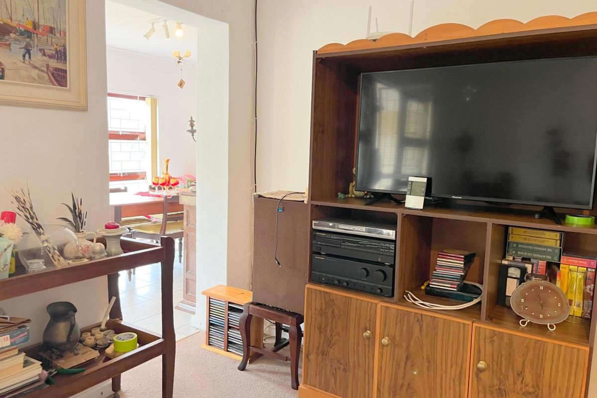 A view from the living area looking through a doorway into the adjacent dining space, featuring carpeted flooring and neutral wall finishes.
