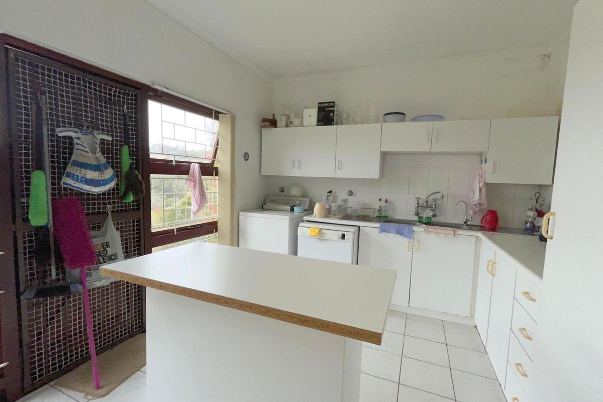 Functional kitchen featuring white cabinetry, tiled flooring, a central island, and a window with security bars overlooking the exterior.