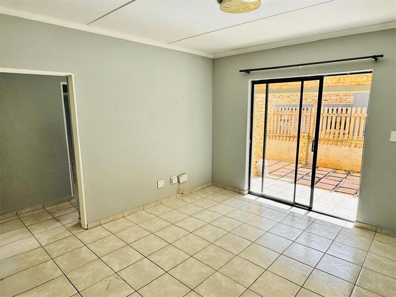 An empty living room featuring ceramic floor tiles and a sliding glass door providing direct access to the rear patio area.