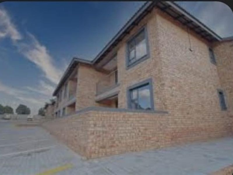 Exterior view of a multi-story townhouse complex featuring face brick construction, paved driveway, and private balconies.