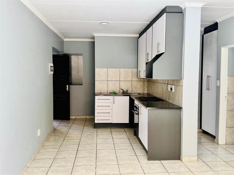 A functional kitchen featuring built-in cabinetry, a tiled backsplash, a built-in oven with hob, and tiled flooring in an open-plan layout.
