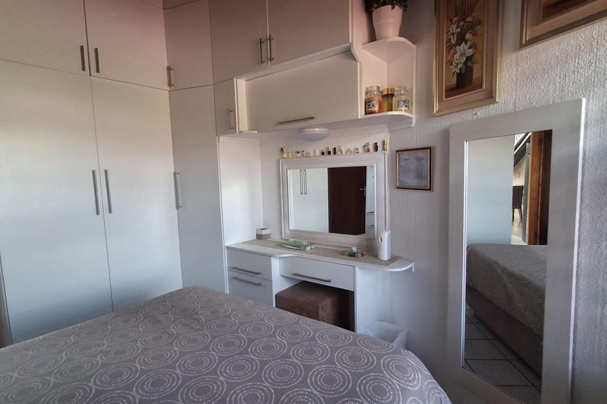 A bedroom featuring extensive built-in cabinetry, including a wardrobe and a integrated vanity unit with a mirror.