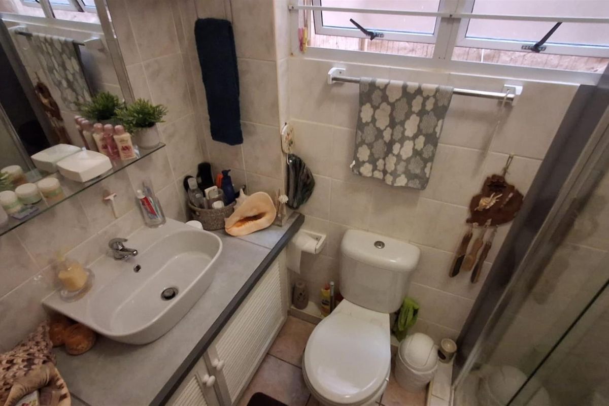 Compact bathroom featuring a wall-mounted vanity with integrated basin, a standard toilet, and a shower enclosure with tiled walls.