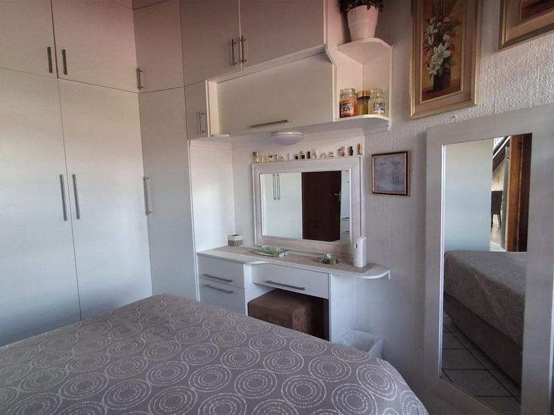 A bedroom featuring extensive built-in cabinetry, including a wardrobe and a integrated vanity unit with a mirror.