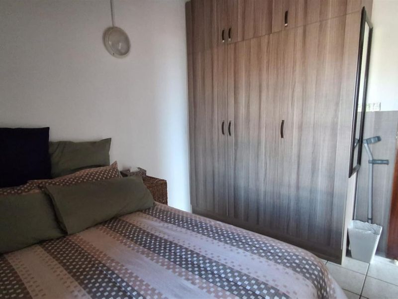 A bedroom featuring built-in wooden cabinetry and tiled flooring, providing functional storage space.