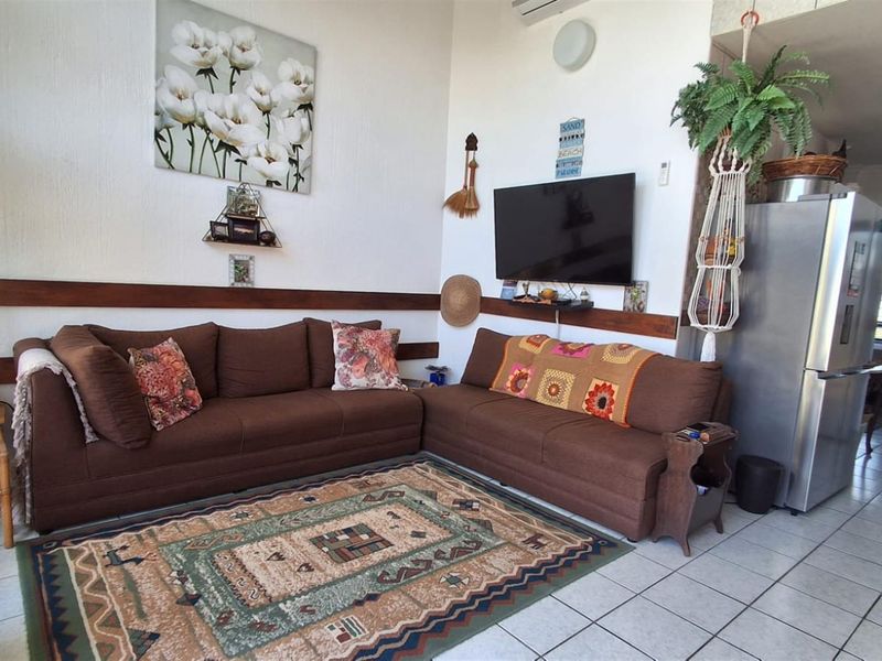 Open plan living area featuring tiled flooring and wall-mounted air conditioning unit, seamlessly connecting to the kitchen space.