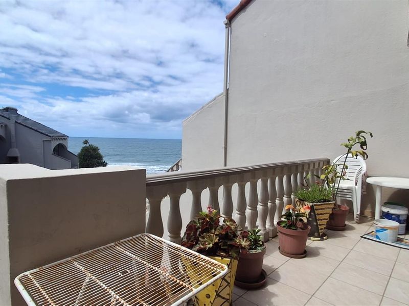 A spacious balcony featuring a classic balustrade, tiled flooring, and expansive ocean views, providing an ideal outdoor space for relaxation.