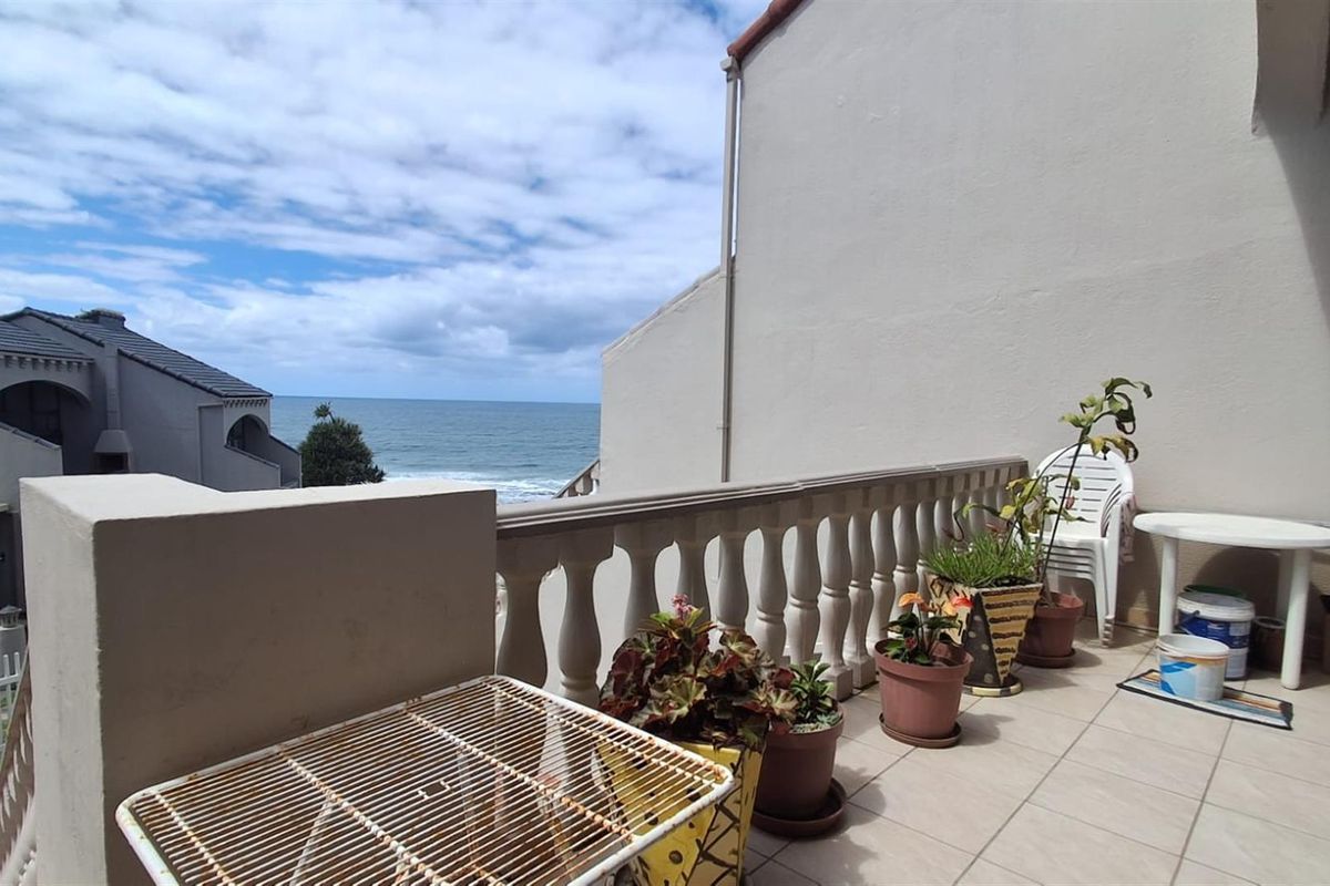 A spacious balcony featuring a classic balustrade, tiled flooring, and expansive ocean views, providing an ideal outdoor space for relaxation.