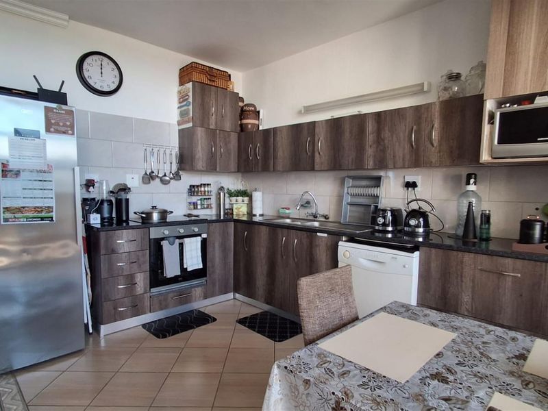 A functional kitchen featuring wood-grain cabinetry, dark countertops, tiled backsplash, and integrated appliances, offering a practical layout for daily meal preparation.
