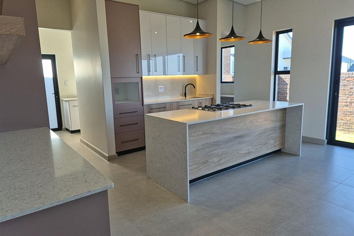 Modern open-plan kitchen featuring a central island with a built-in gas hob, stone countertops, and sleek cabinetry with integrated lighting.
