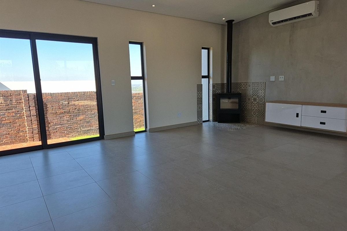 Spacious living area featuring large sliding glass doors, a modern freestanding fireplace with decorative tiling, and a wall-mounted air conditioning unit.