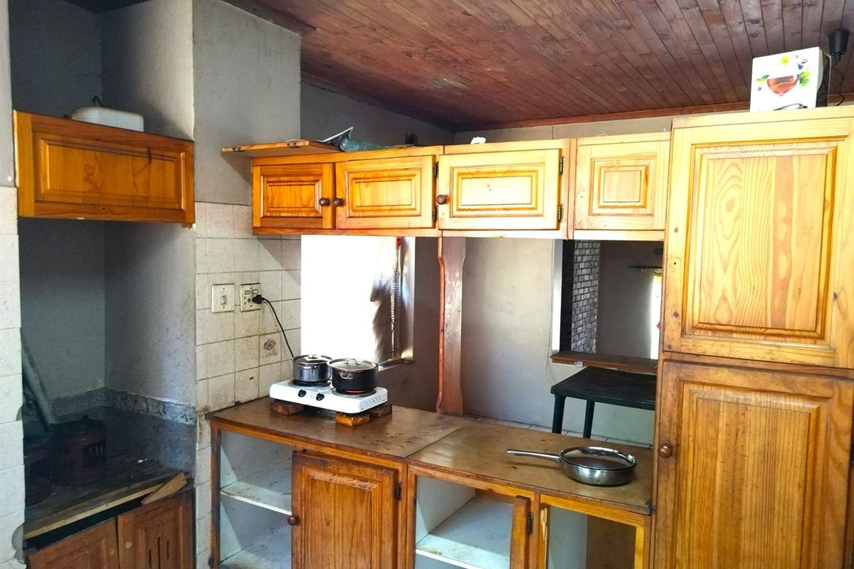 A dated kitchen featuring wooden cabinetry, a timber-paneled ceiling, and tiled splashbacks, offering a functional layout with potential for modernization.