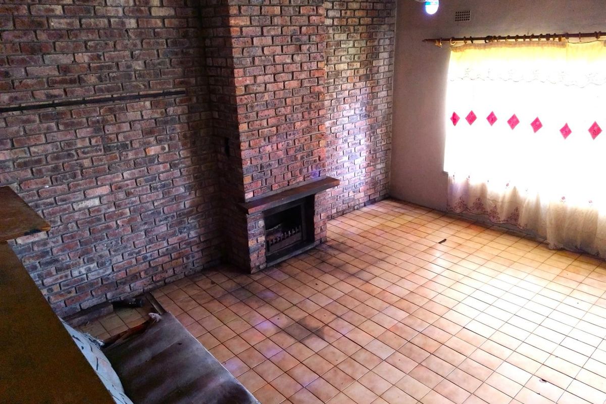 Living room featuring a prominent face-brick feature wall with a built-in fireplace and ceramic floor tiling.