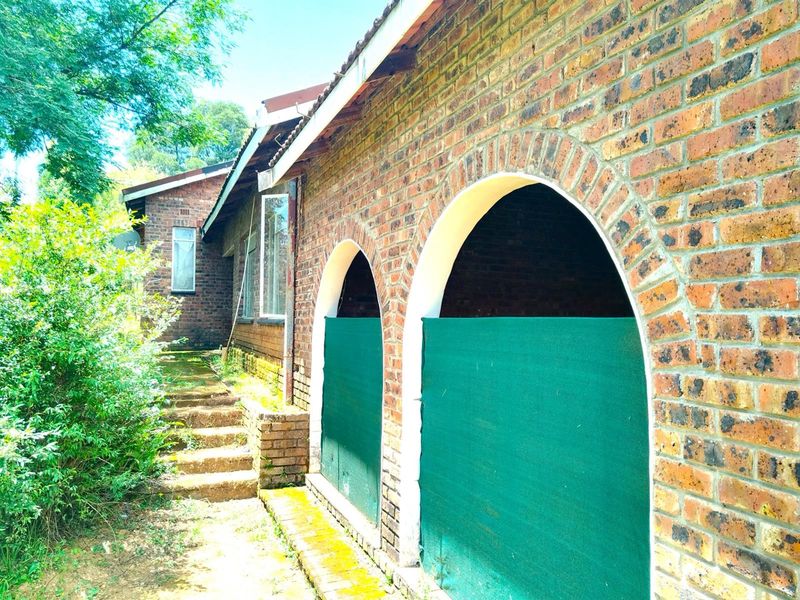 Exterior view of the property featuring a brick facade with arched openings and concrete steps leading along the side of the house.