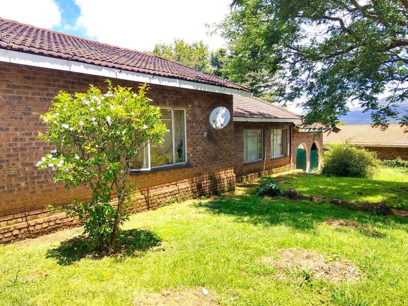 A view of the rear exterior of the house featuring face brick walls, a tiled roof, and a spacious garden area.