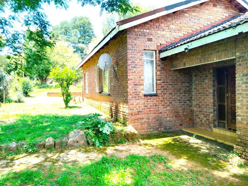 A side view of a face-brick house featuring a covered entrance, established garden, and satellite dish mounted on the exterior wall.