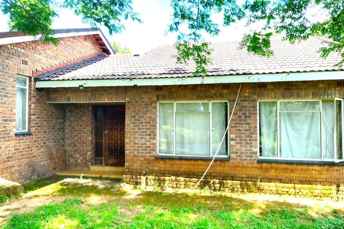 A classic face-brick exterior facade featuring a tiled roof, large windows, and a covered entrance area set within a garden.