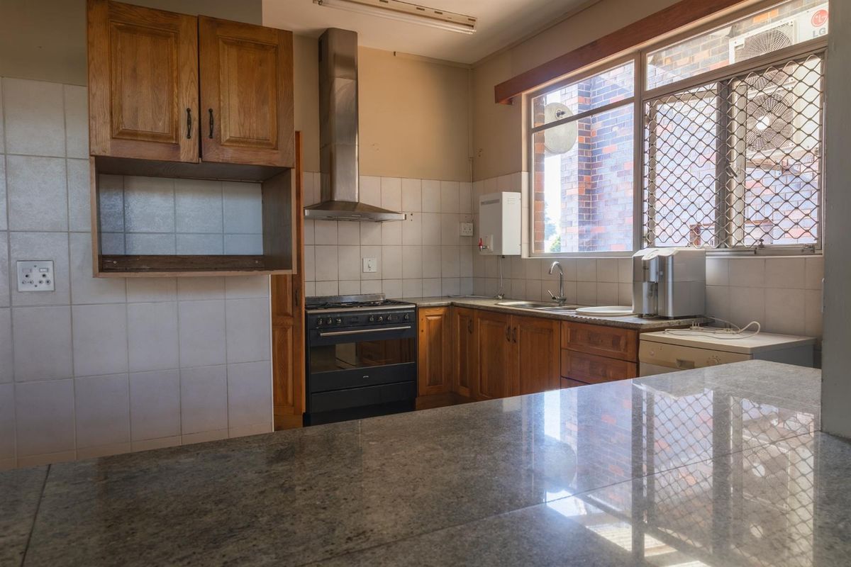 A functional kitchen featuring wooden cabinetry, granite countertops, a gas stove with an extractor fan, and a tiled backsplash.