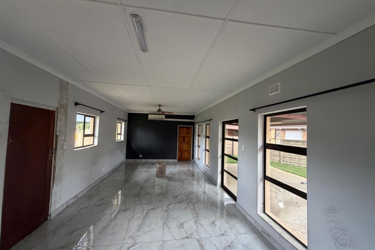Spacious, empty living area featuring modern marble-look tiled flooring, air conditioning, and large windows providing ample natural light.