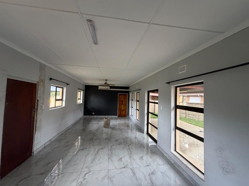 Spacious, empty living area featuring modern marble-look tiled flooring, air conditioning, and large windows providing ample natural light.