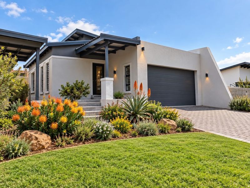 Modern front elevation featuring a paved driveway, integrated garage, and well-maintained landscaped garden with a covered entrance.