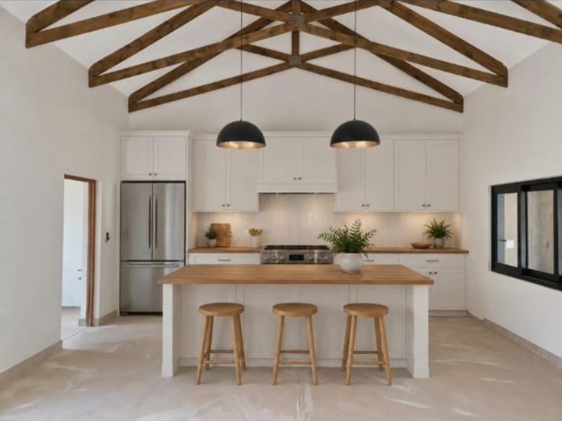 Modern kitchen featuring a large island, white cabinetry, and striking exposed timber ceiling beams, creating a bright and functional culinary space.