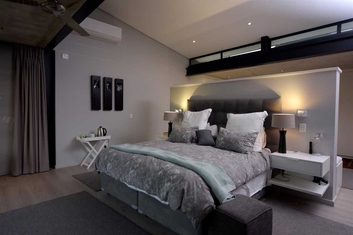 A modern, well-appointed bedroom featuring a split-level ceiling design, integrated lighting, and a wall-mounted air conditioning unit.