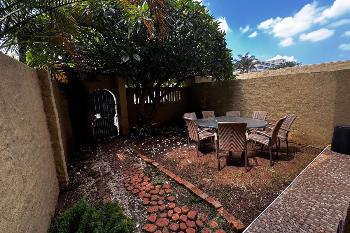 A private rear courtyard featuring a brick pathway, pebble paving, and high boundary walls, providing a secluded outdoor space.