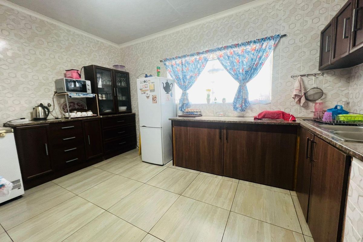 A functional kitchen featuring dark wood cabinetry, tiled flooring, and patterned wall tiles, providing ample storage and workspace.