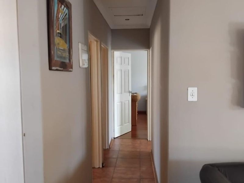 A neutral-toned hallway featuring tiled flooring, recessed downlighting, and coved cornicing, providing access to multiple rooms within the townhouse.