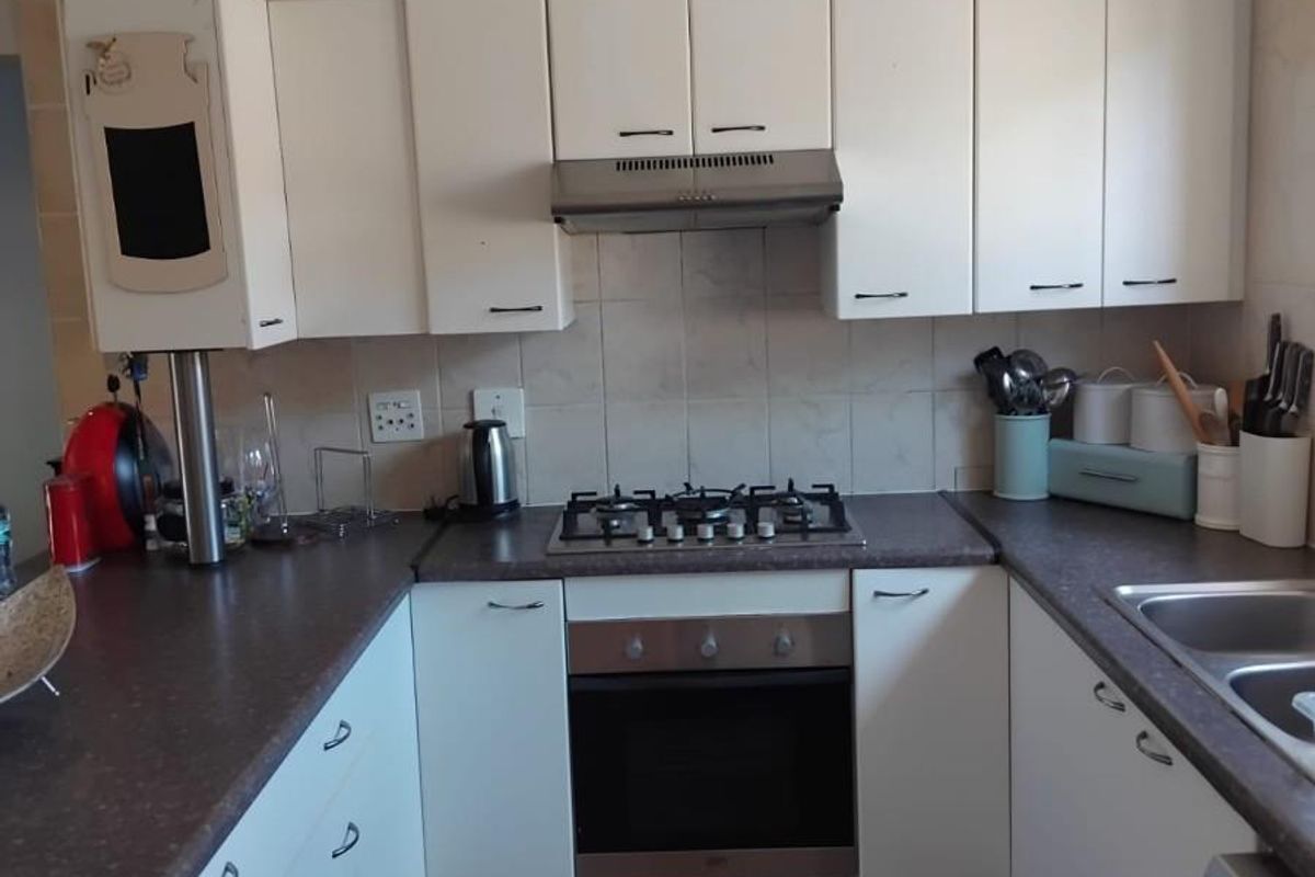 Functional kitchen featuring white cabinetry, gas hob, built-in oven, extractor fan, and double bowl sink with tiled splashback and flooring.