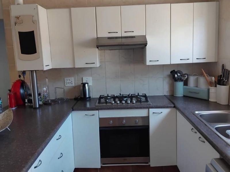 Functional kitchen featuring white cabinetry, gas hob, built-in oven, extractor fan, and double bowl sink with tiled splashback and flooring.