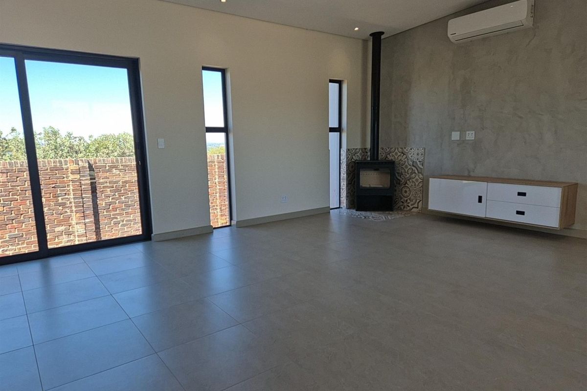 Spacious living area featuring large sliding glass doors, a modern fireplace with decorative tiling, and a wall-mounted air conditioning unit.