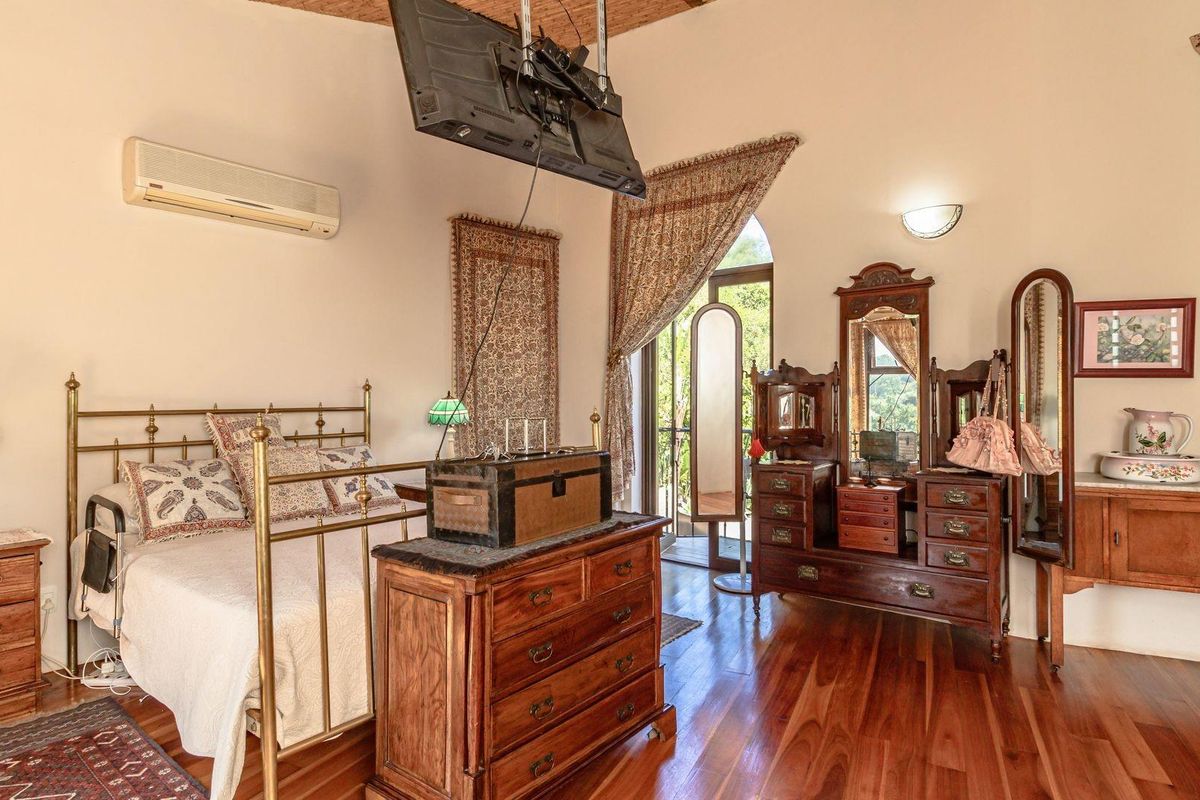 Spacious bedroom featuring polished timber flooring, high vaulted ceilings, and direct access to an outdoor balcony area.