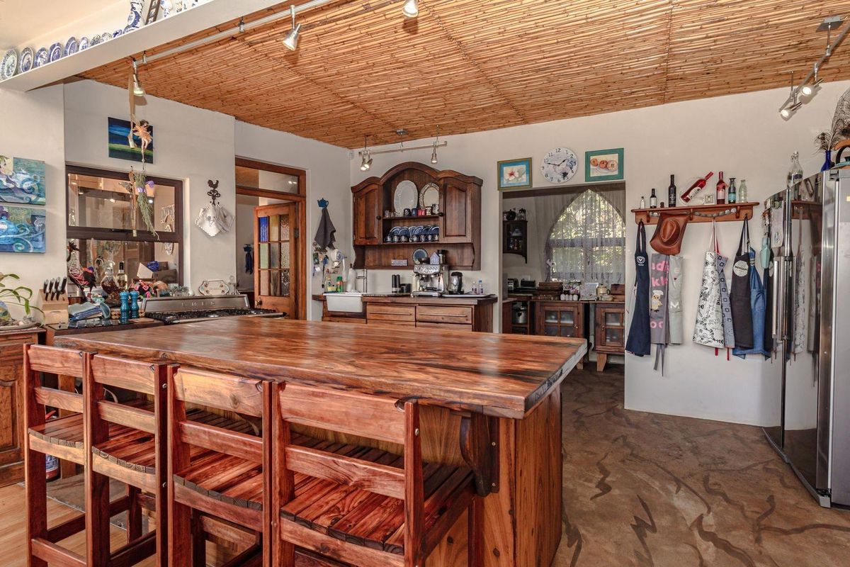 Rustic kitchen featuring a large wooden island, custom timber cabinetry, a farmhouse sink, and a unique bamboo-style ceiling finish with track lighting.