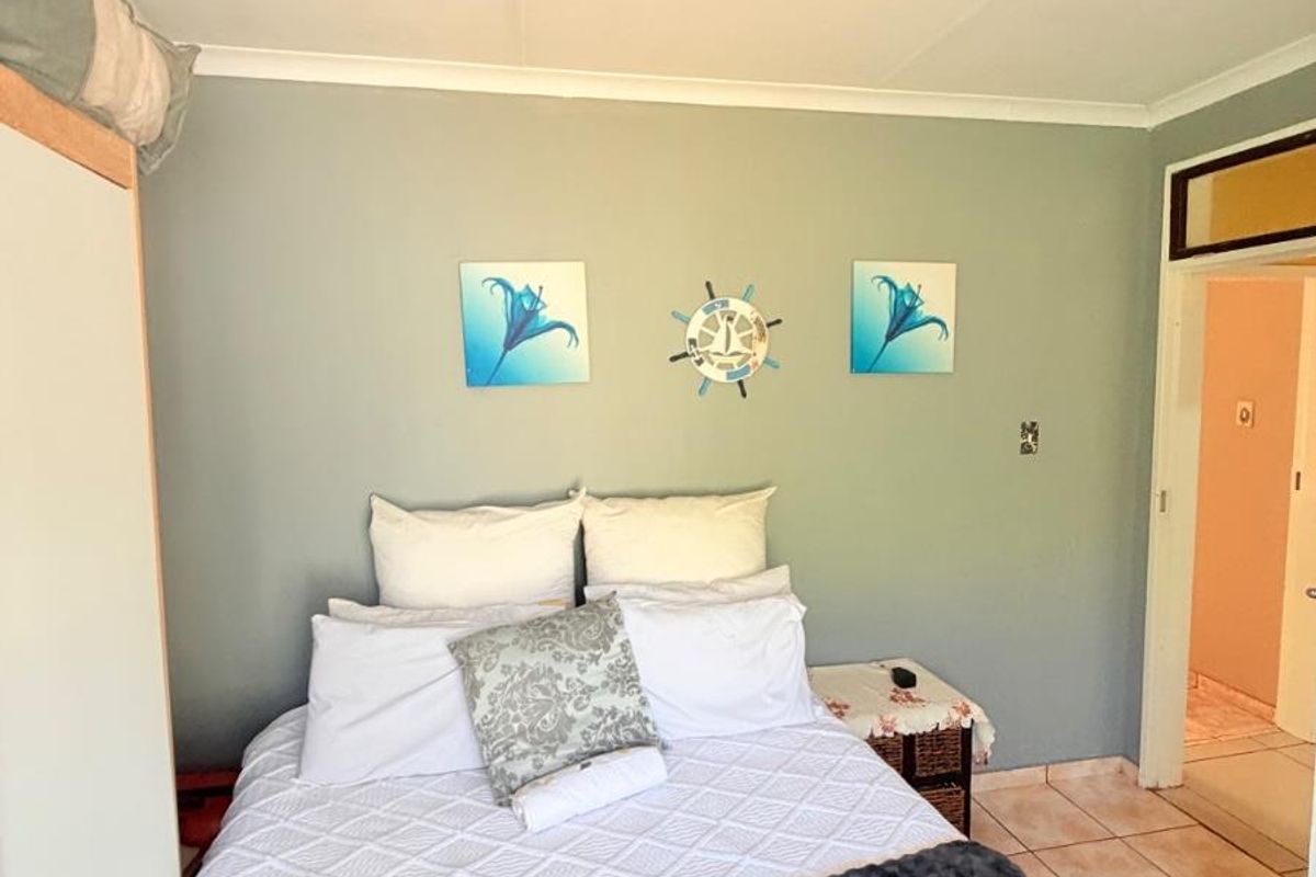 A bedroom featuring tiled flooring, a built-in wardrobe, and access to an adjoining room.