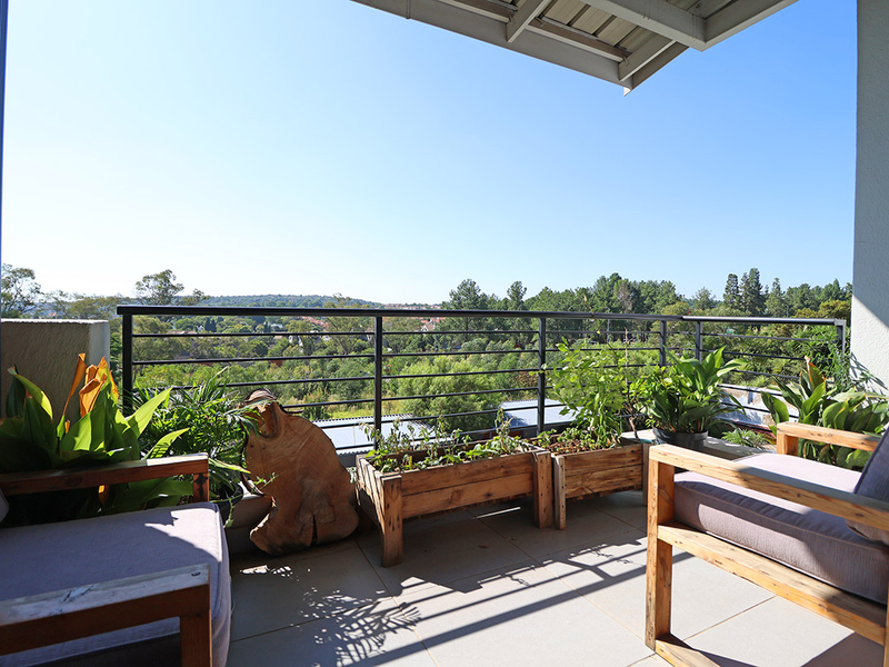 A covered balcony featuring tiled flooring and a metal balustrade, offering elevated views of the surrounding landscape.