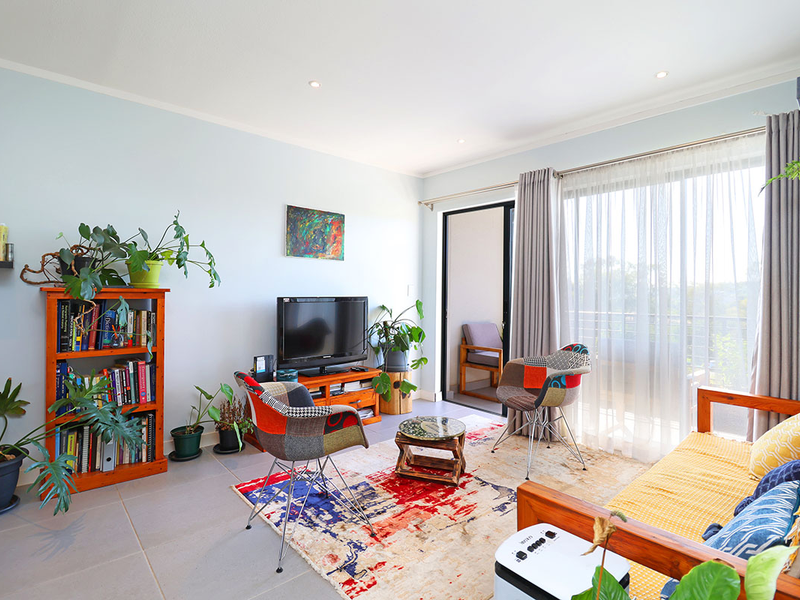 Bright living room featuring tiled flooring, recessed downlighting, and a large sliding glass door providing direct access to the balcony.