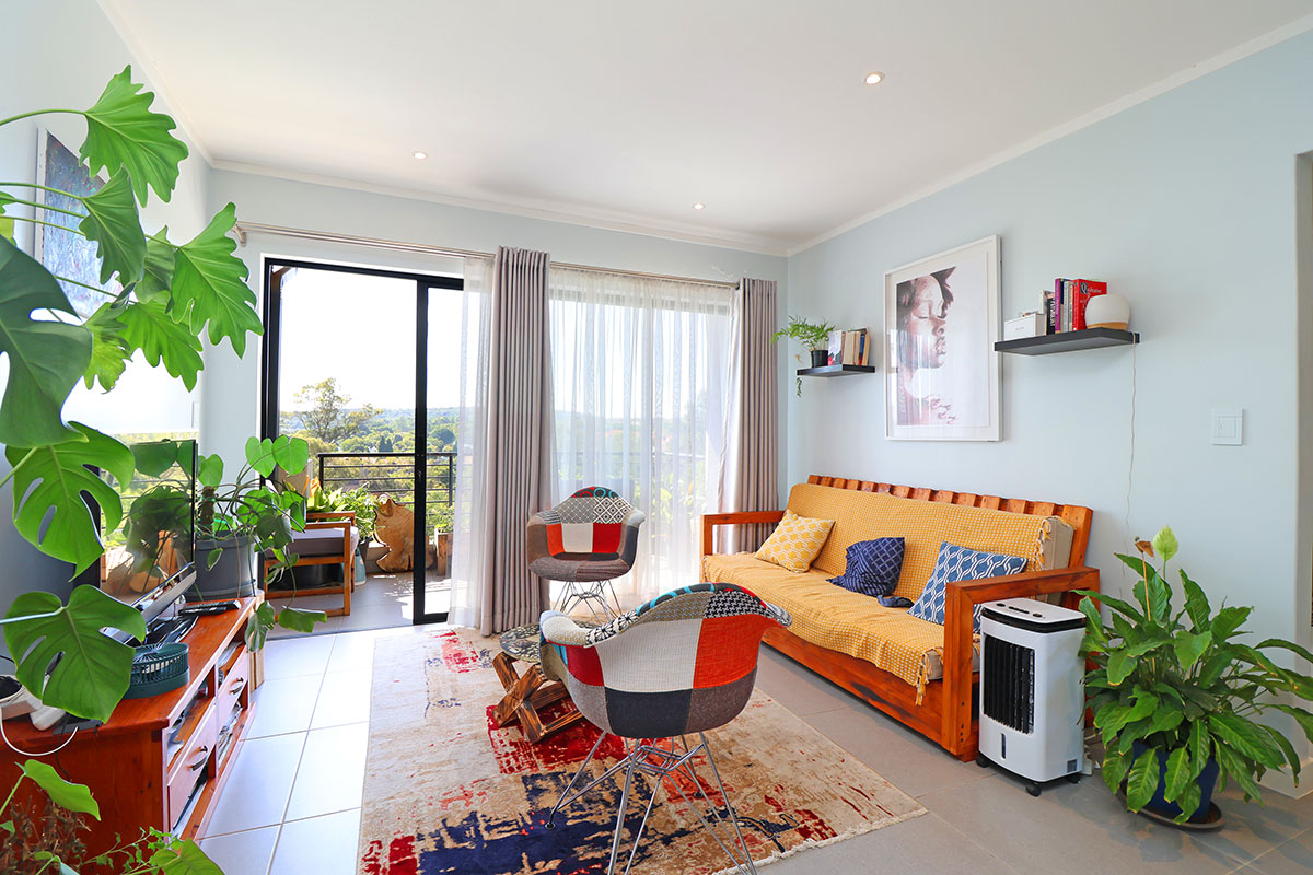 A bright and well-maintained living room featuring tiled floors, recessed lighting, and a large sliding glass door providing access to the balcony.