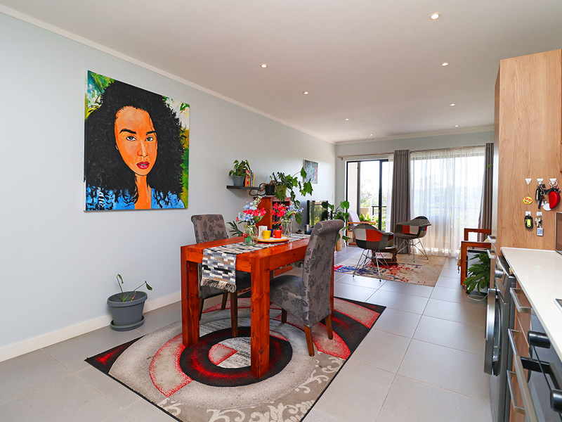 An open-plan living and dining area featuring tiled floors, recessed lighting, and a modern kitchen with built-in cabinetry and stone countertops.